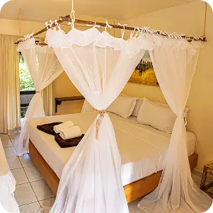 foto da cama com véu em cima da suíte deluxe